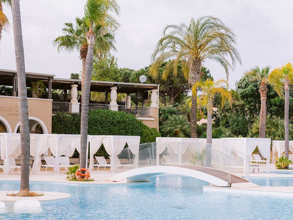 Pool and cabanas among palm trees at Forte Village Resort