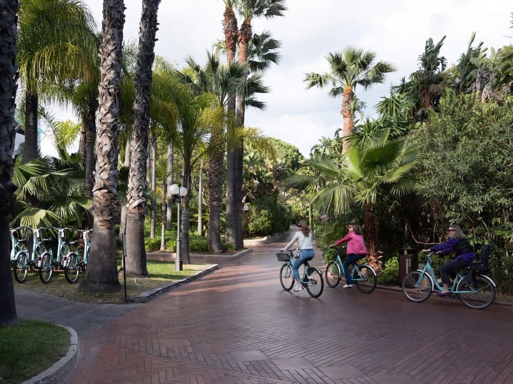 Guests cycling along a palm-lined path at Forte Village Resort