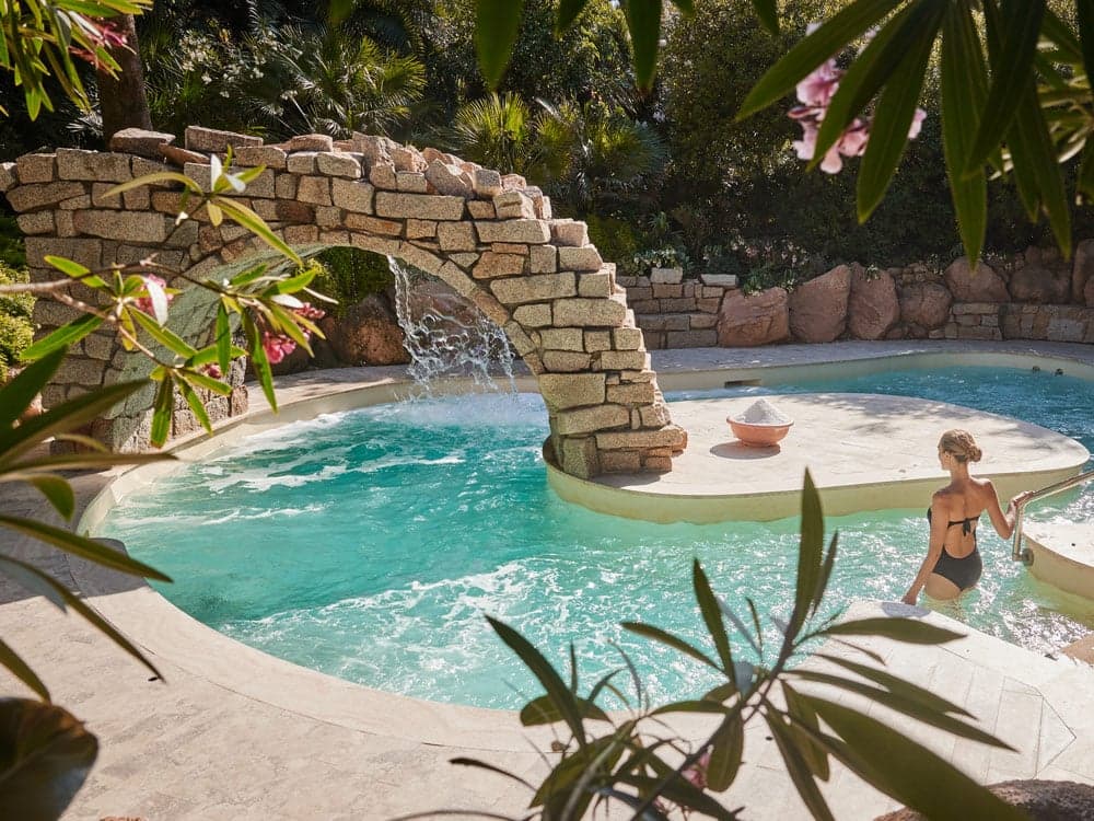 Swimmer in a rock-arched pool at Forte Village Resort