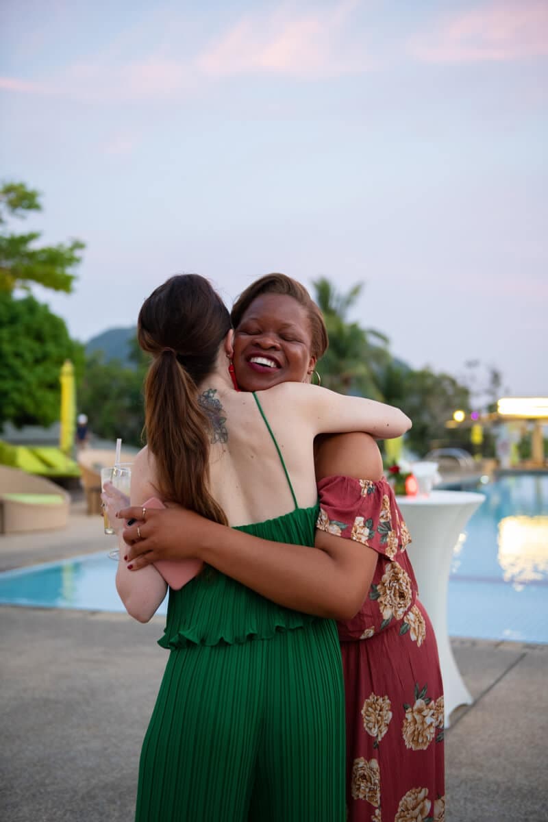 Two delegates hugging beside a pool