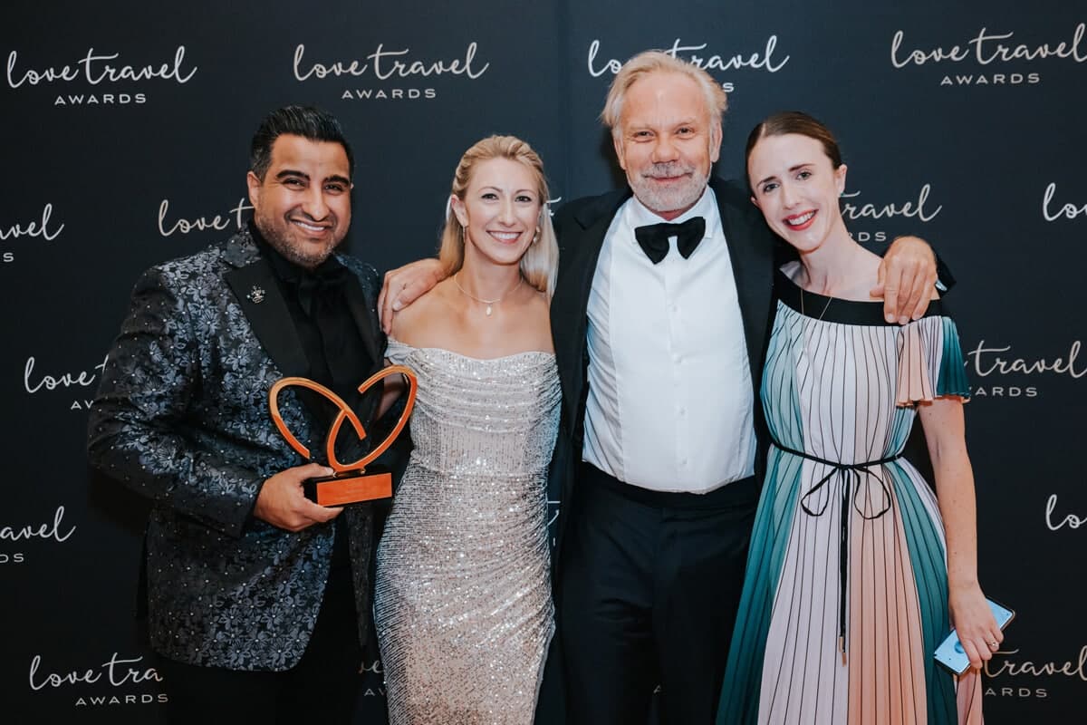 Love Travel Awards winner holding a trophy with three guests