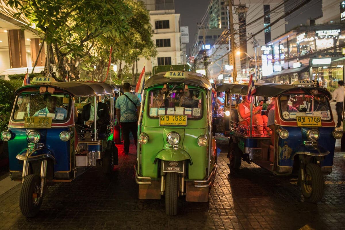 Tuk-tuks lined up on a street at night