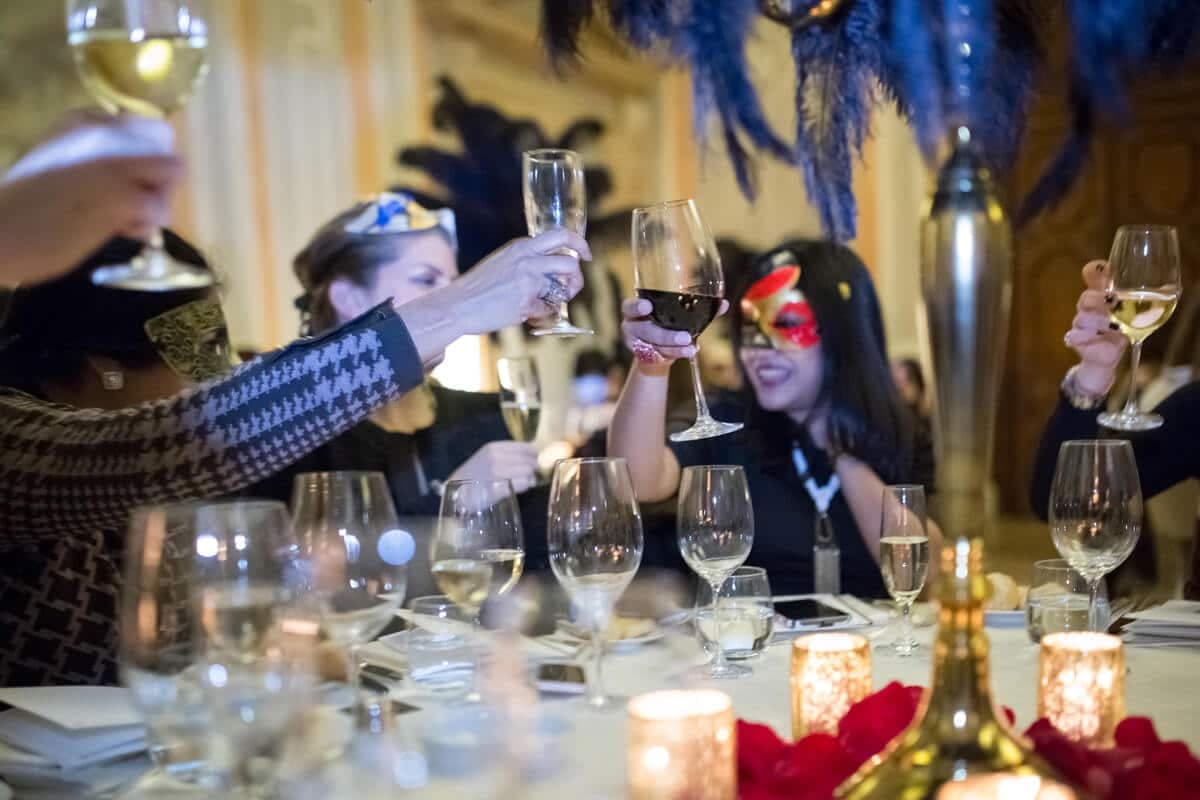 Masked guests raising a toast at a masquerade dinner
