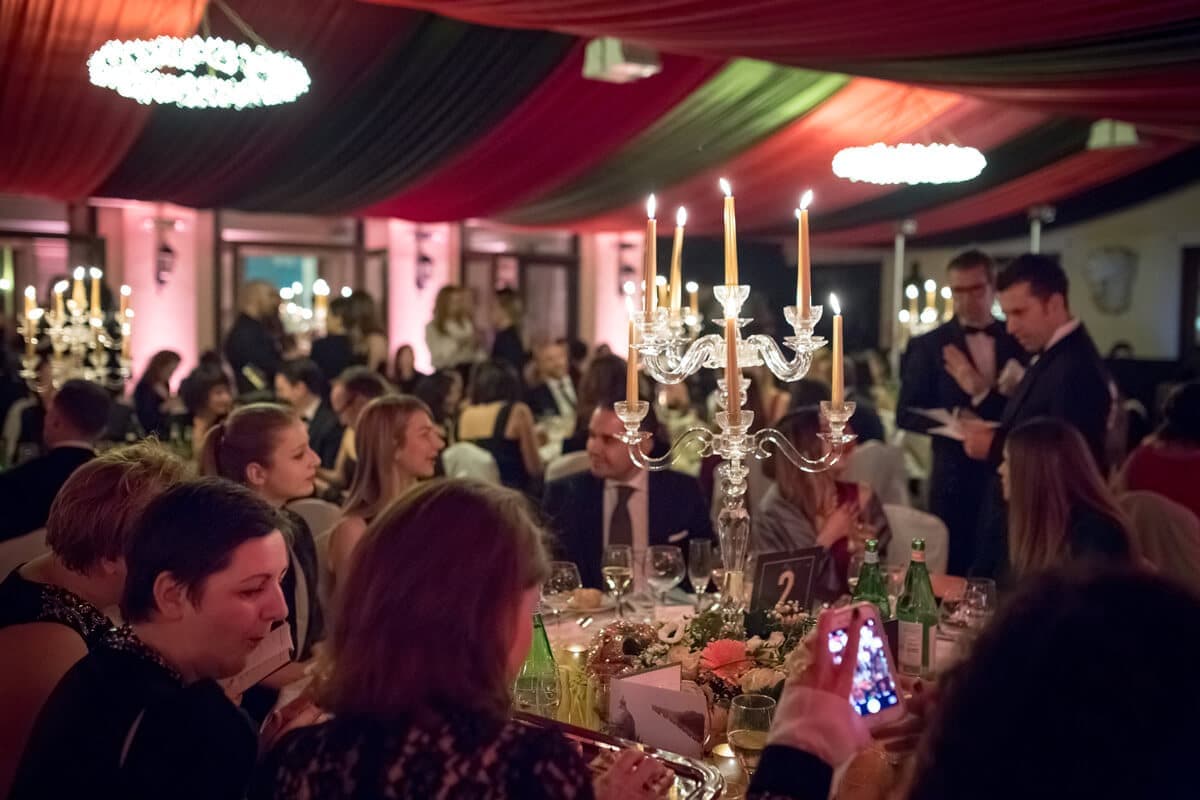 Guests at a candlelit dinner under a draped marquee