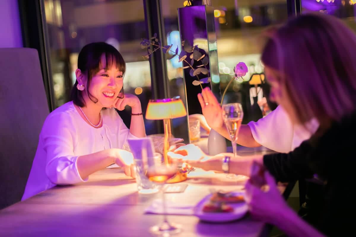 Two delegates laughing at a table in purple light